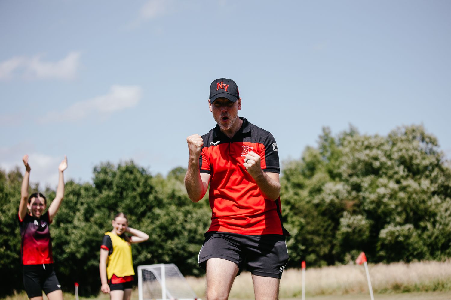 Athletic event participant in red shirt gesturing during outdoor competition.