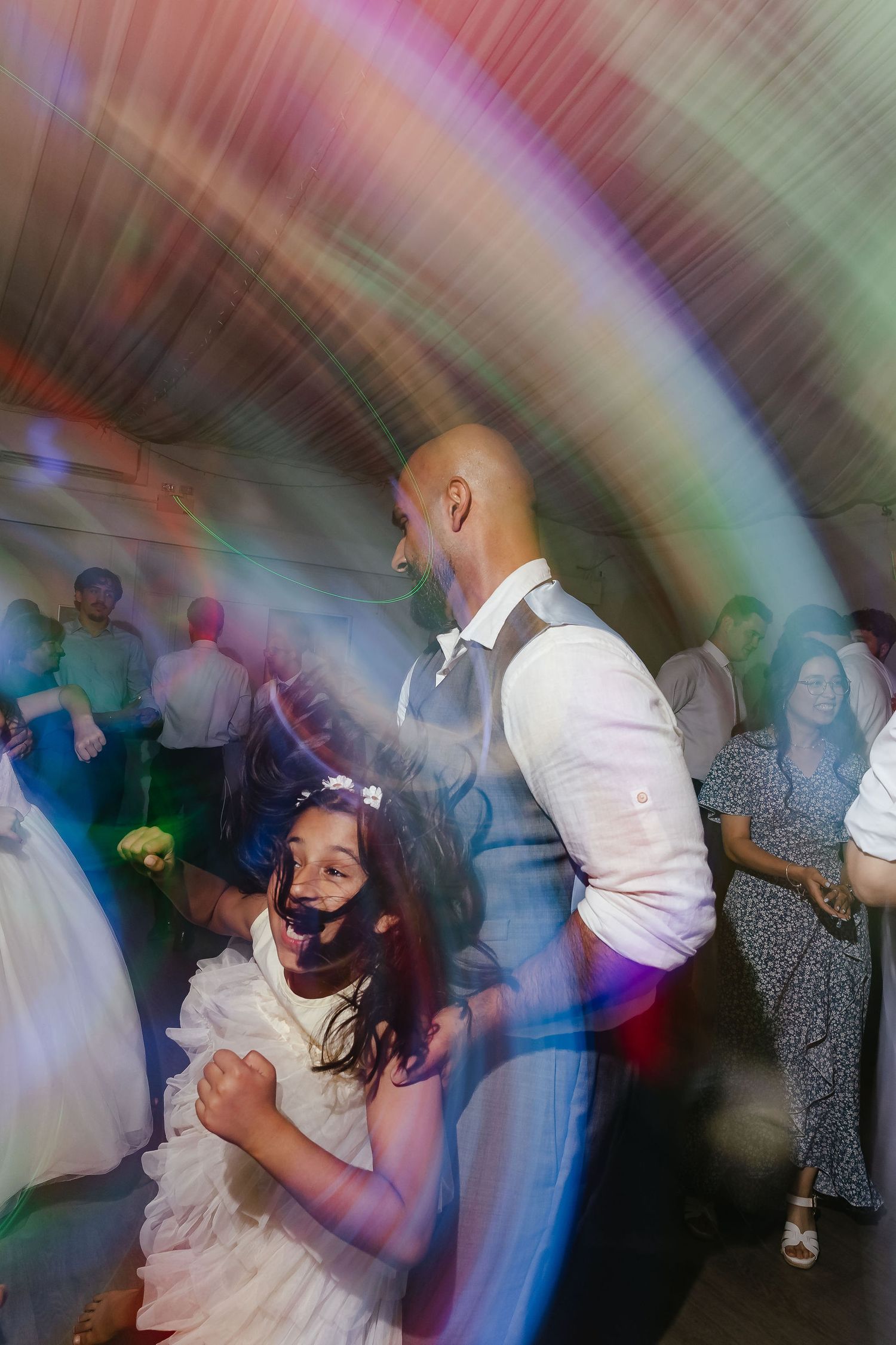 Bride and groom dancing together at a wedding reception with colorful disco lights swirling around them.