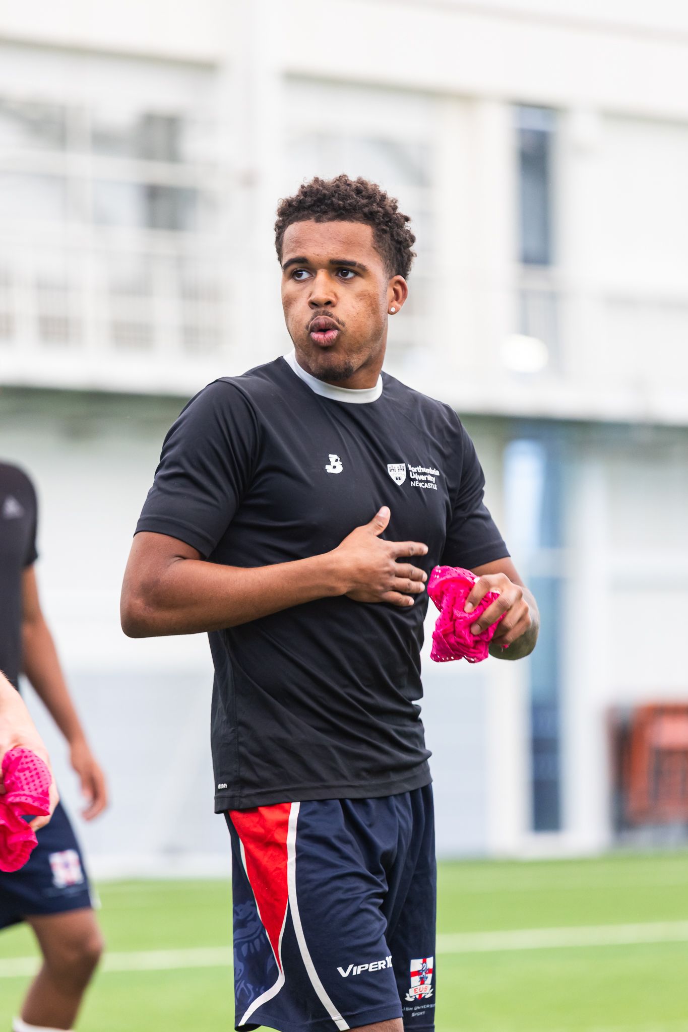Rugby player carrying a pink training pad during practice drills.