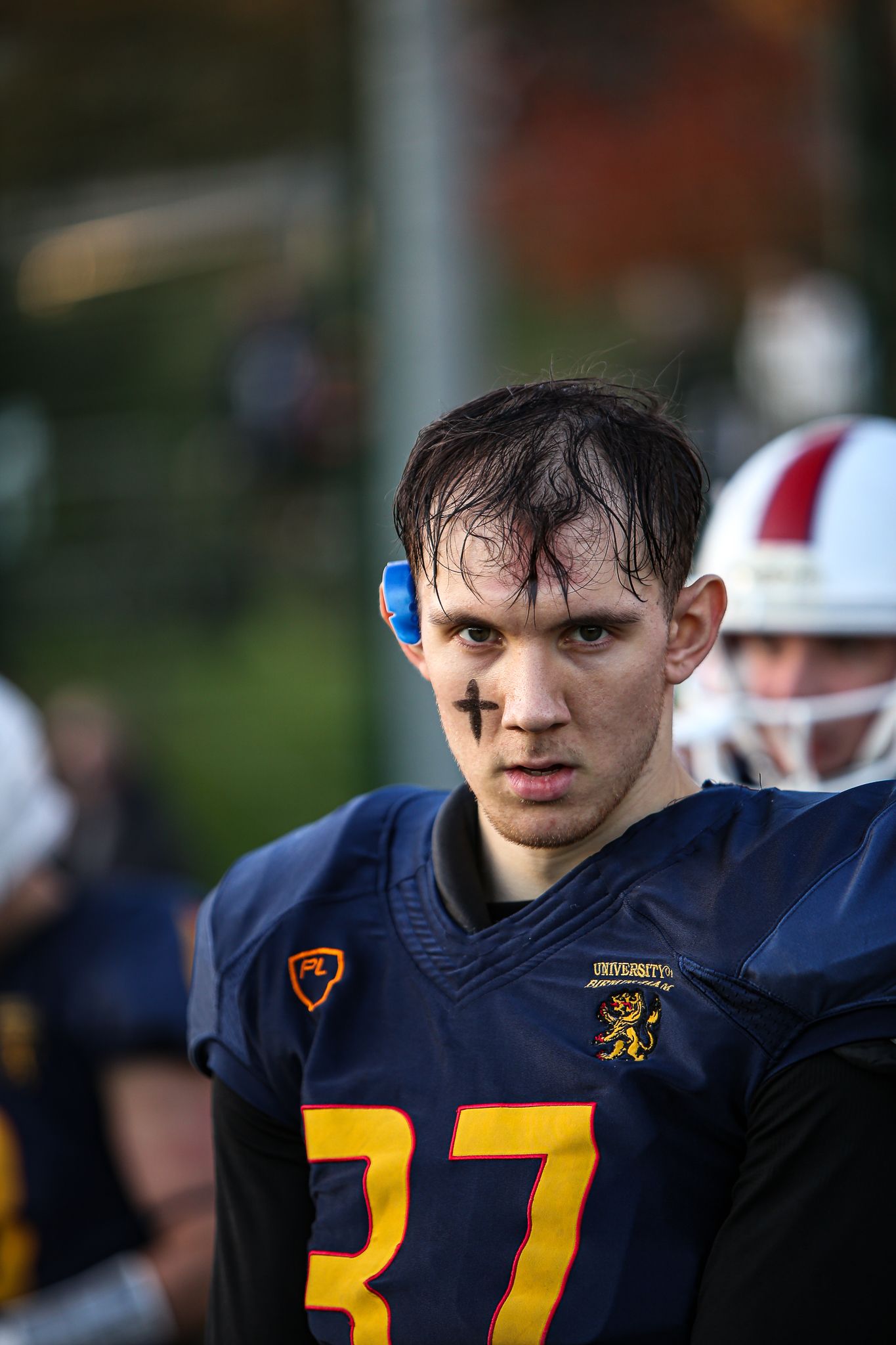 A football player in a navy blue jersey with yellow numbers looks intensely at the camera during a game.