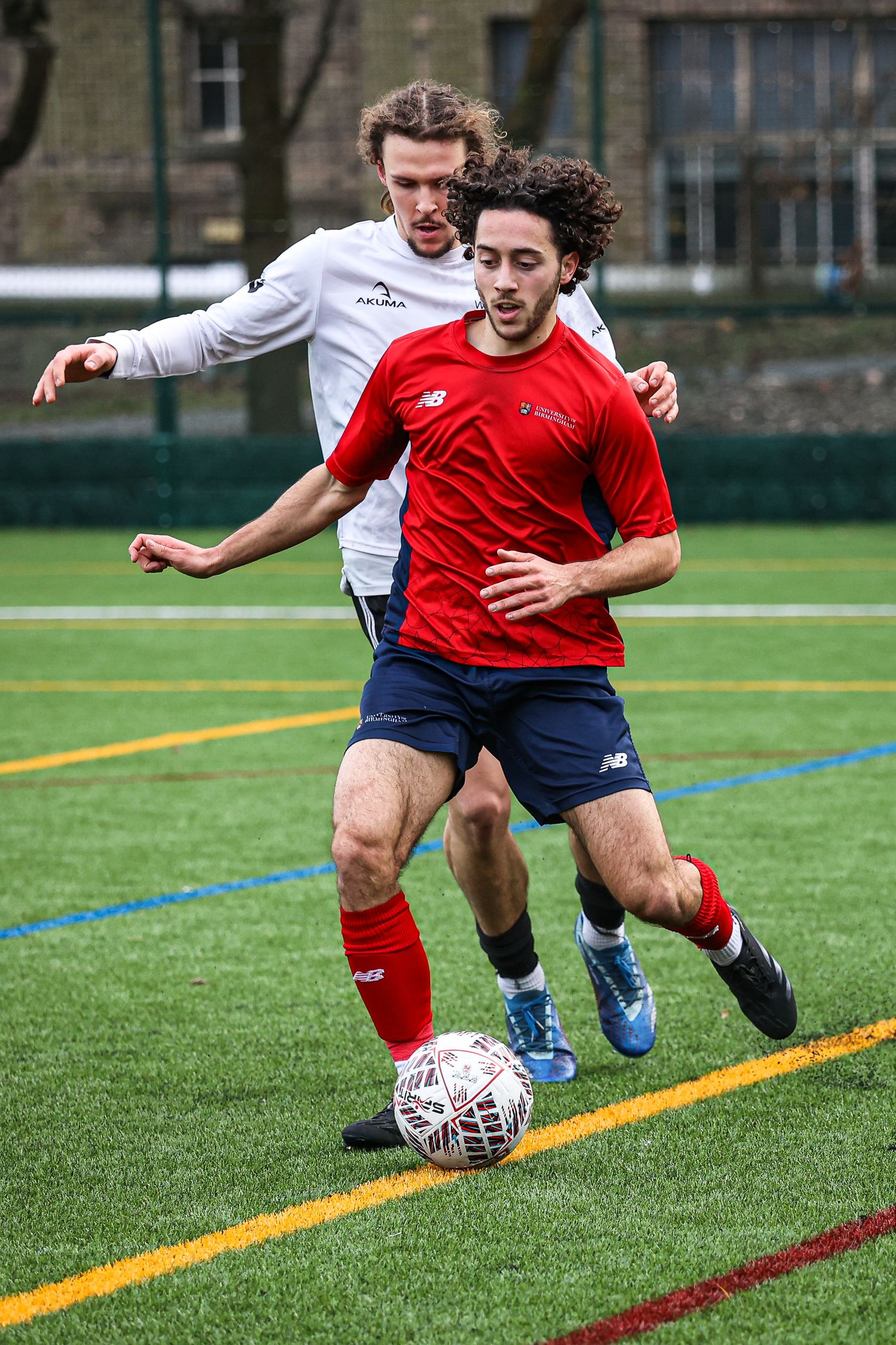 Two soccer players battling for possession during a competitive match on artificial turf.