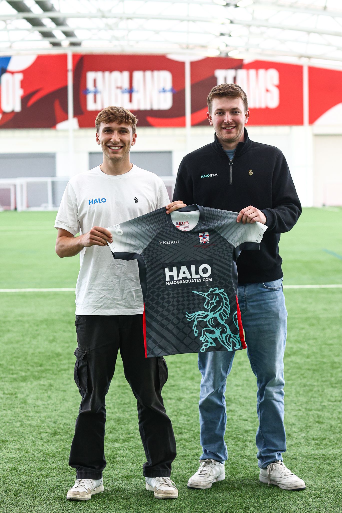 Athletes displaying new black soccer jerseys with teal accents and Halo branding on an indoor field.
