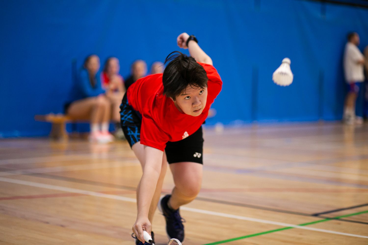 Athletes practicing drills on blue indoor court with wooden floor.