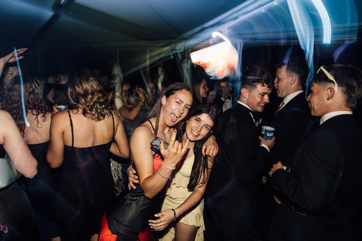 Nightclub scene with crowd dancing under blue lighting.