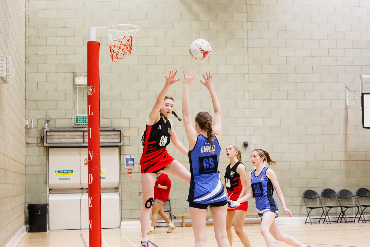 Indoor netball court with players competing during a match.