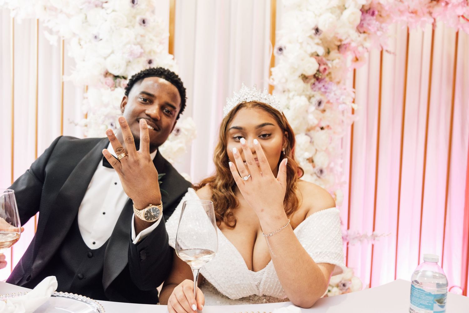Wedding celebration with pink floral backdrop and elegant white draping.