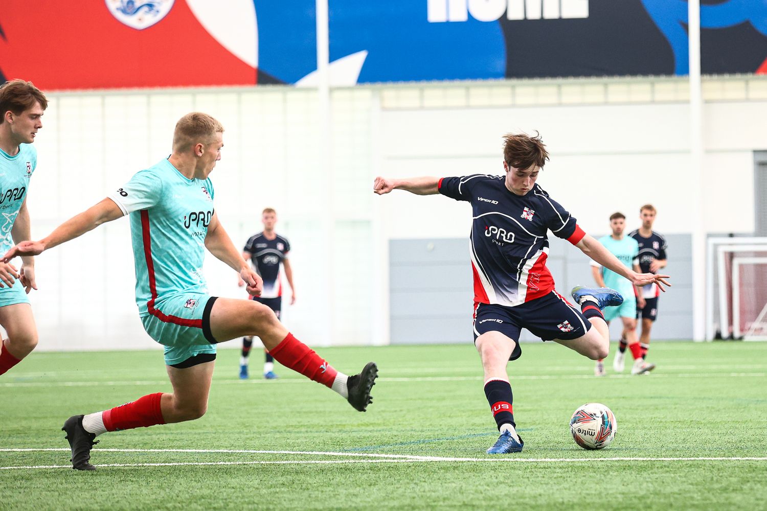 Soccer players practicing ball control drills on an indoor turf field.