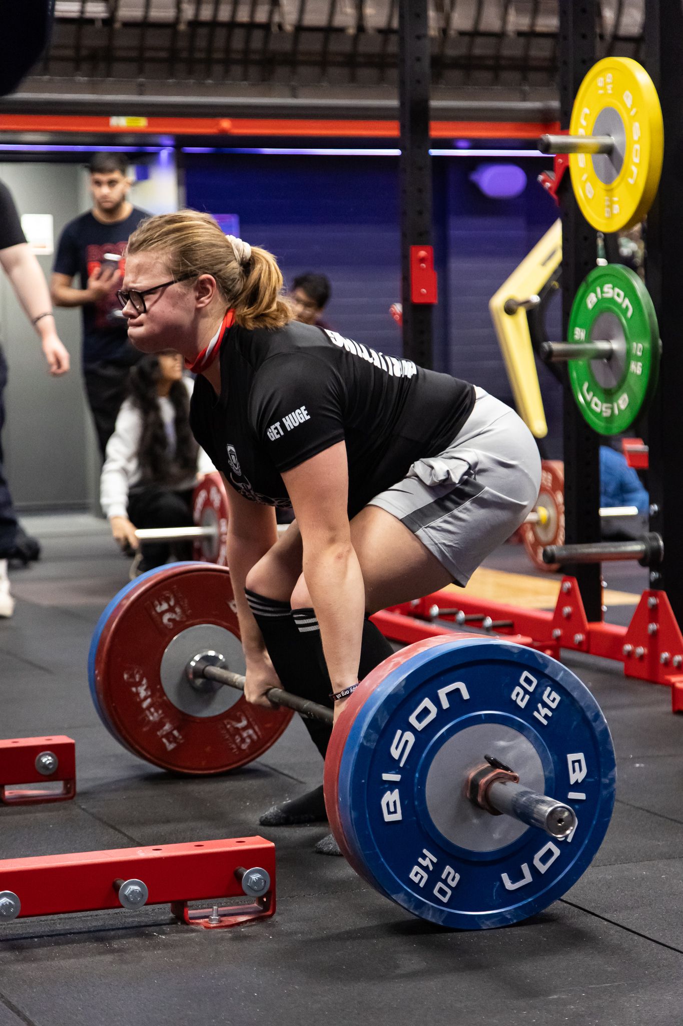 Athletes performing deadlift exercises with blue and red weight plates in a CrossFit gym setting.