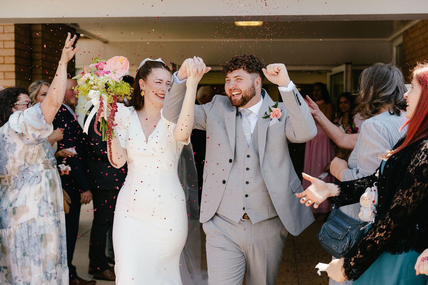 Happy bride and groom celebrating with confetti outside church after wedding ceremony.