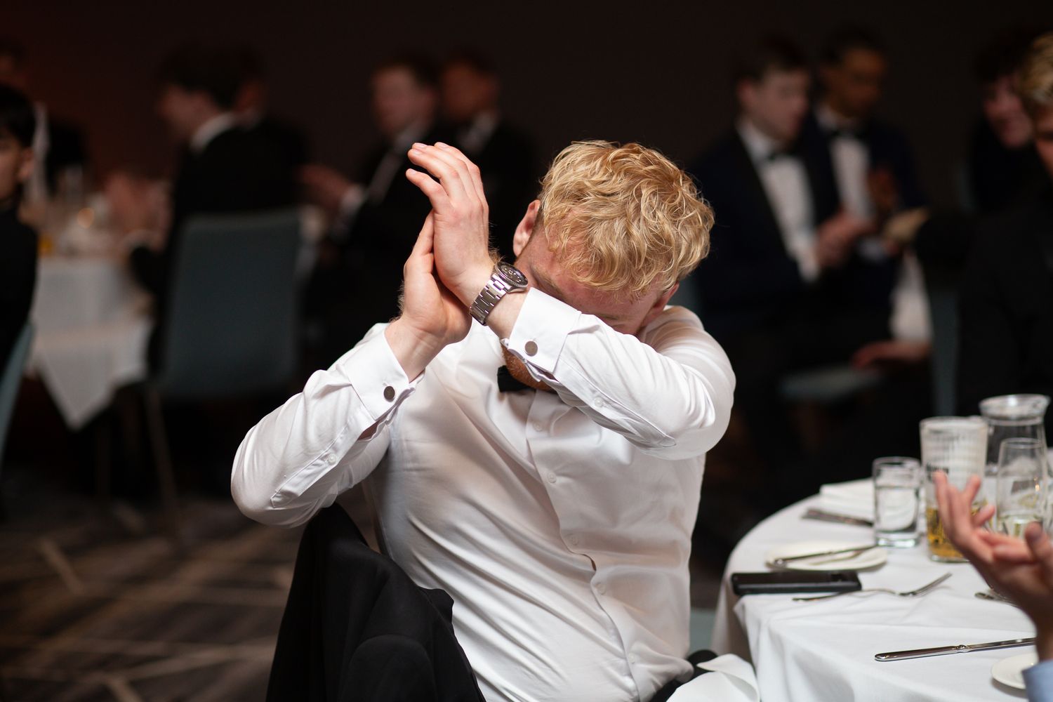 Formal dinner event attendees sharing laughs and embraces at a banquet.