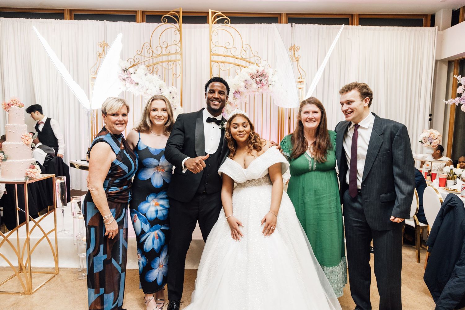 Wedding reception guests dancing joyfully in an elegantly decorated ballroom with white draping.
