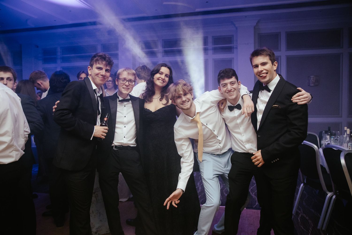 Energetic party scene with people dancing and celebrating under blue nightclub lighting.