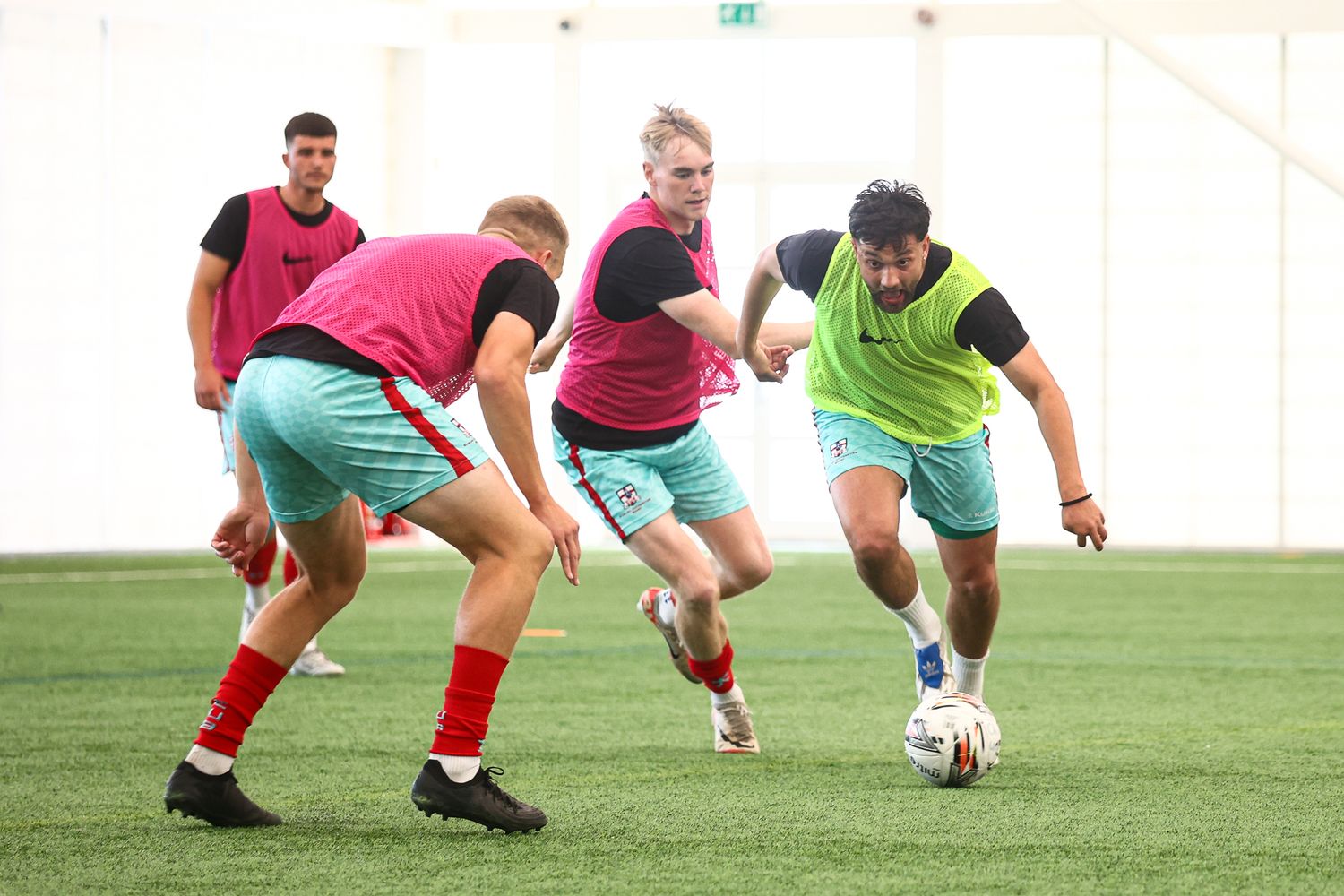 Athletes practicing low stance drills on artificial turf field during training session.