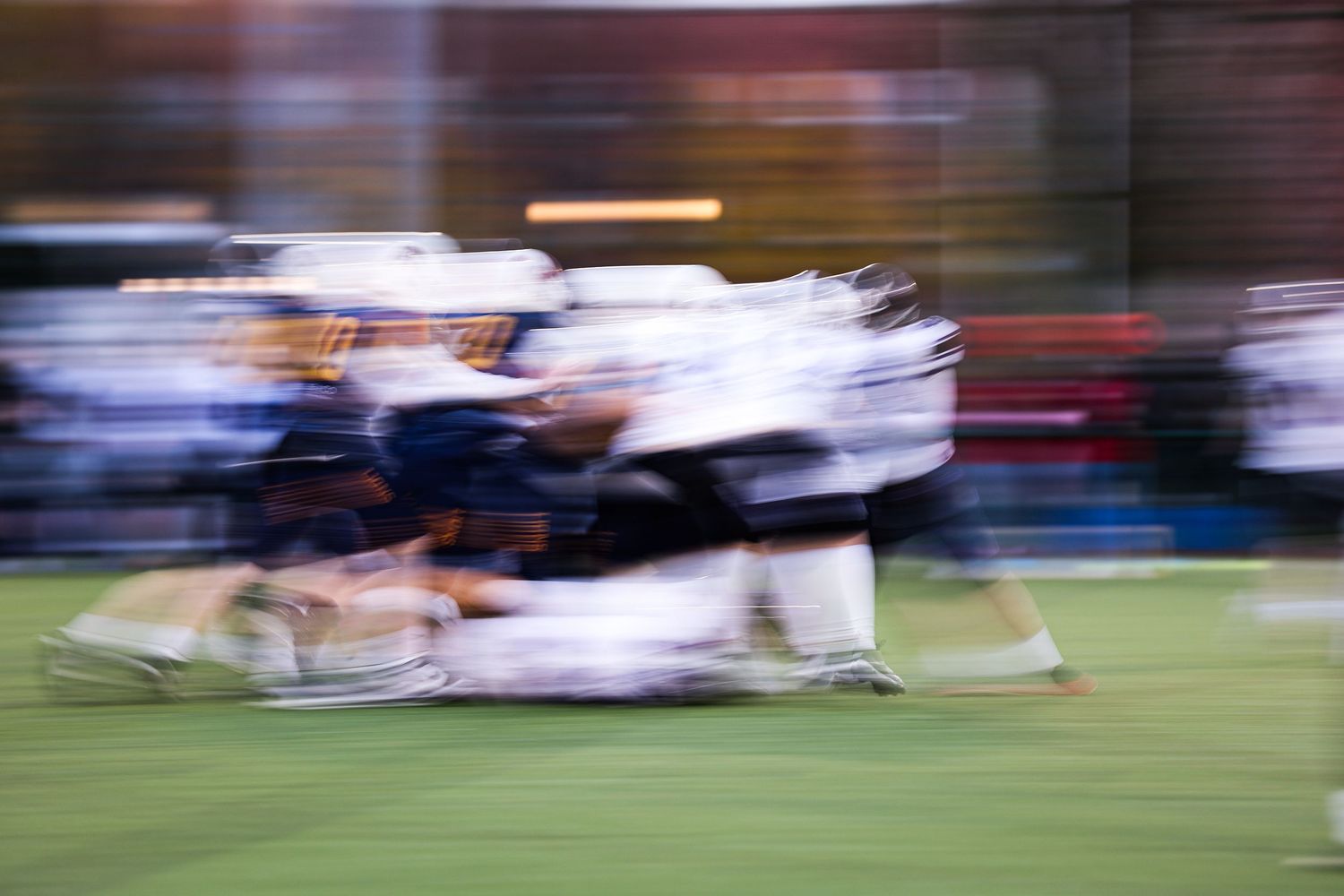 Motion blur of players running across a sports field during an intense game.