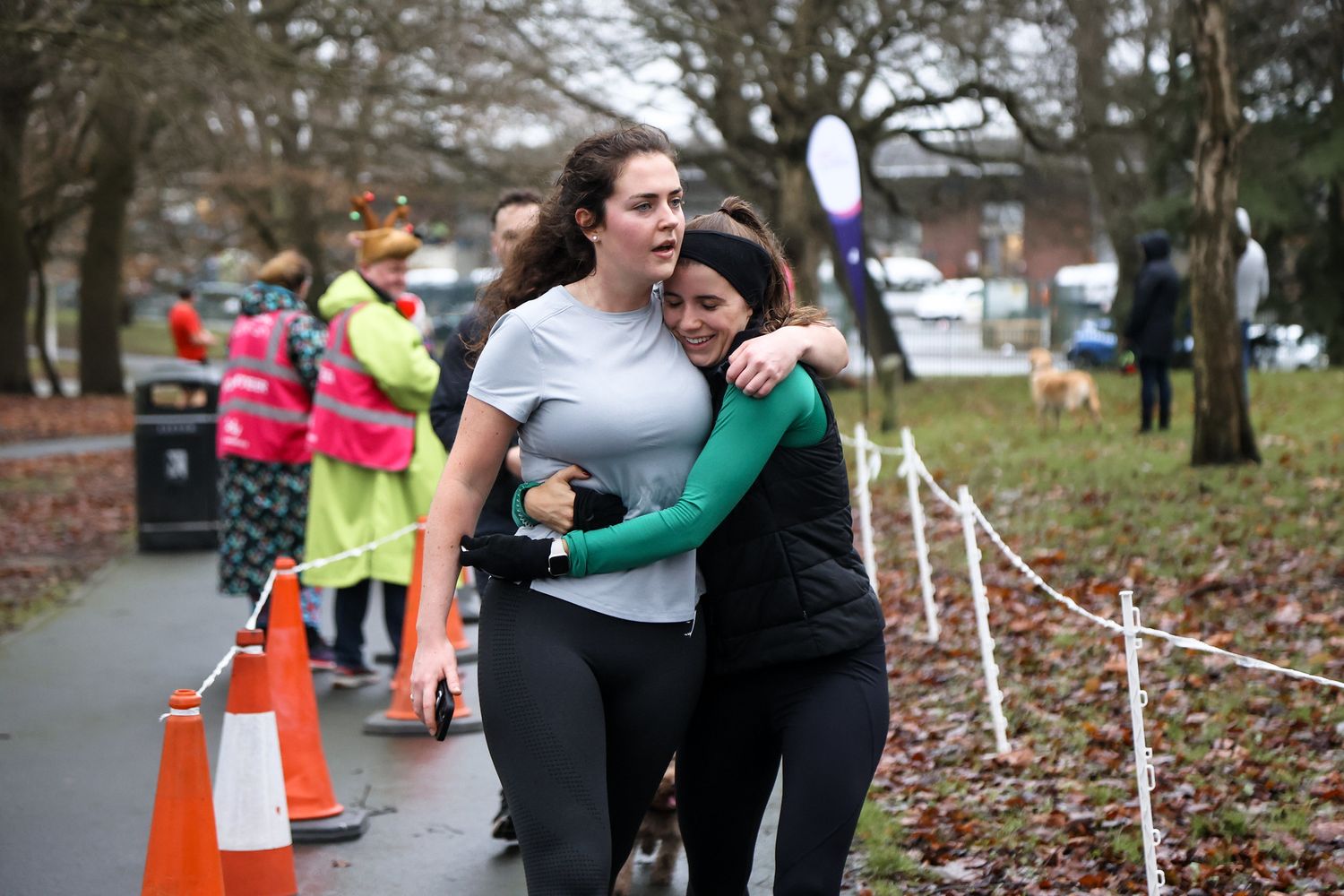 Participants sharing an emotional embrace during an outdoor running event.