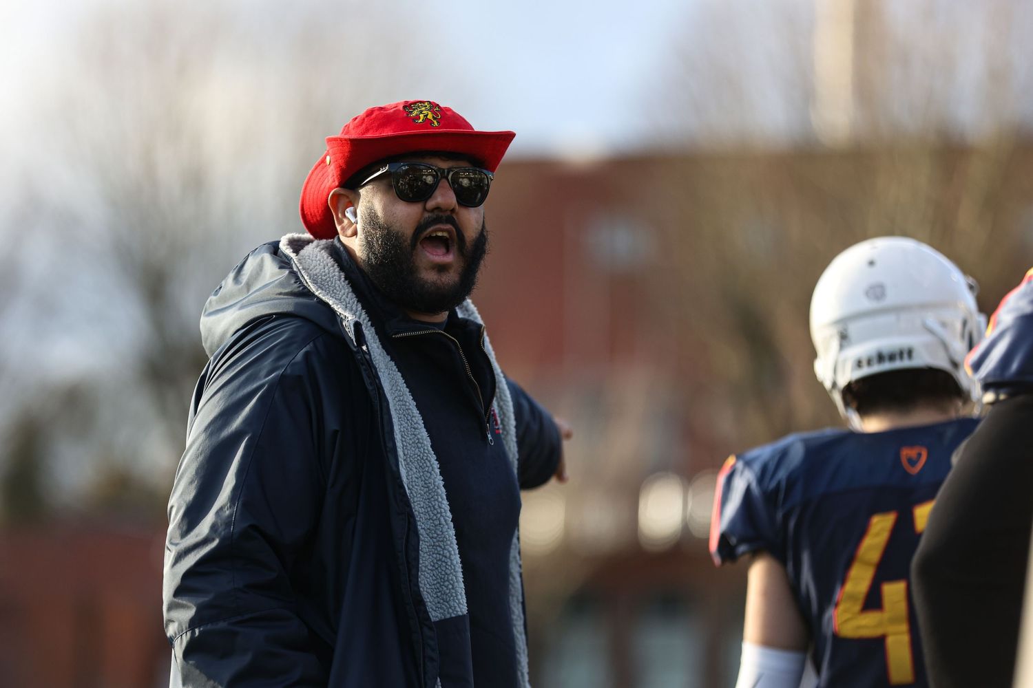 Football coaches directing players during practice on a fall afternoon.