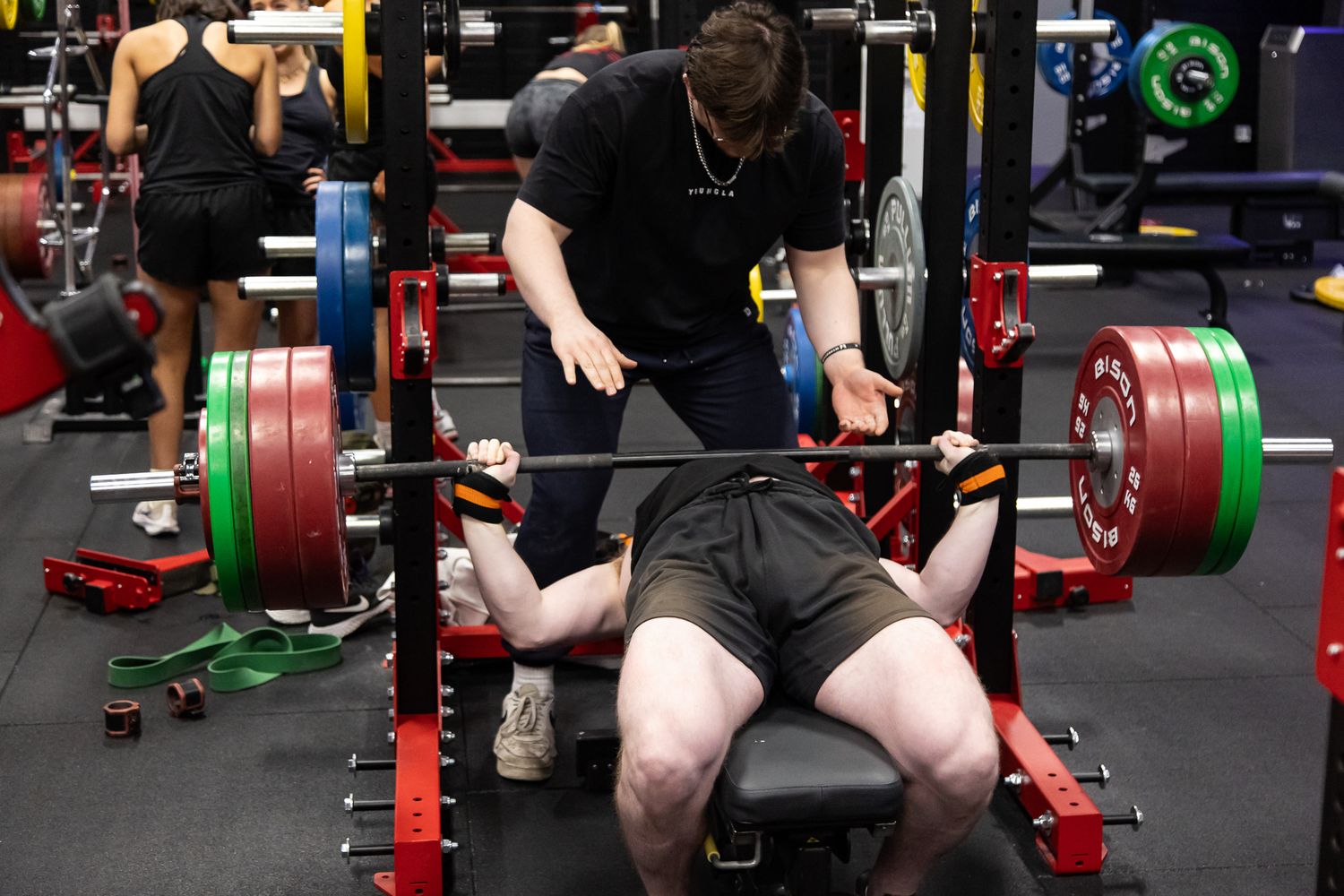 Multiple athletes performing synchronized deadlifts with colorful weight plates during training.