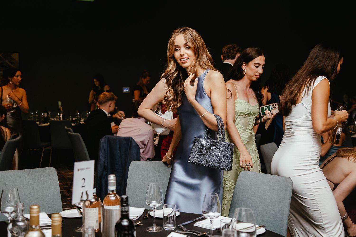 Party guests celebrating at dimly lit indoor reception with drinks.
