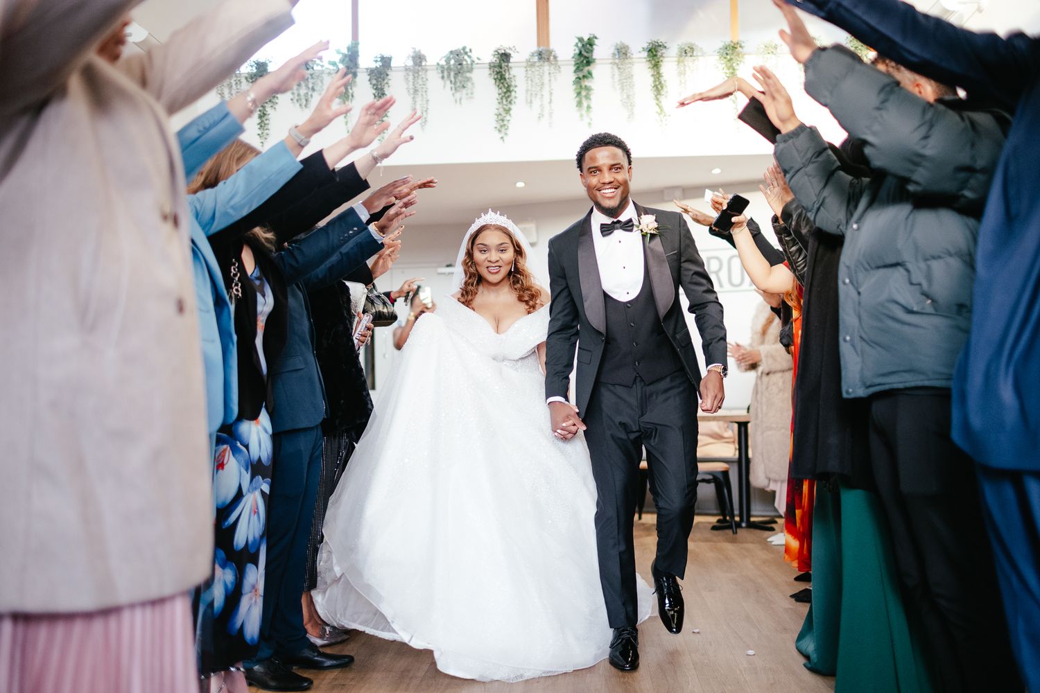 Wedding party celebrates with raised arms during a joyful reception moment.