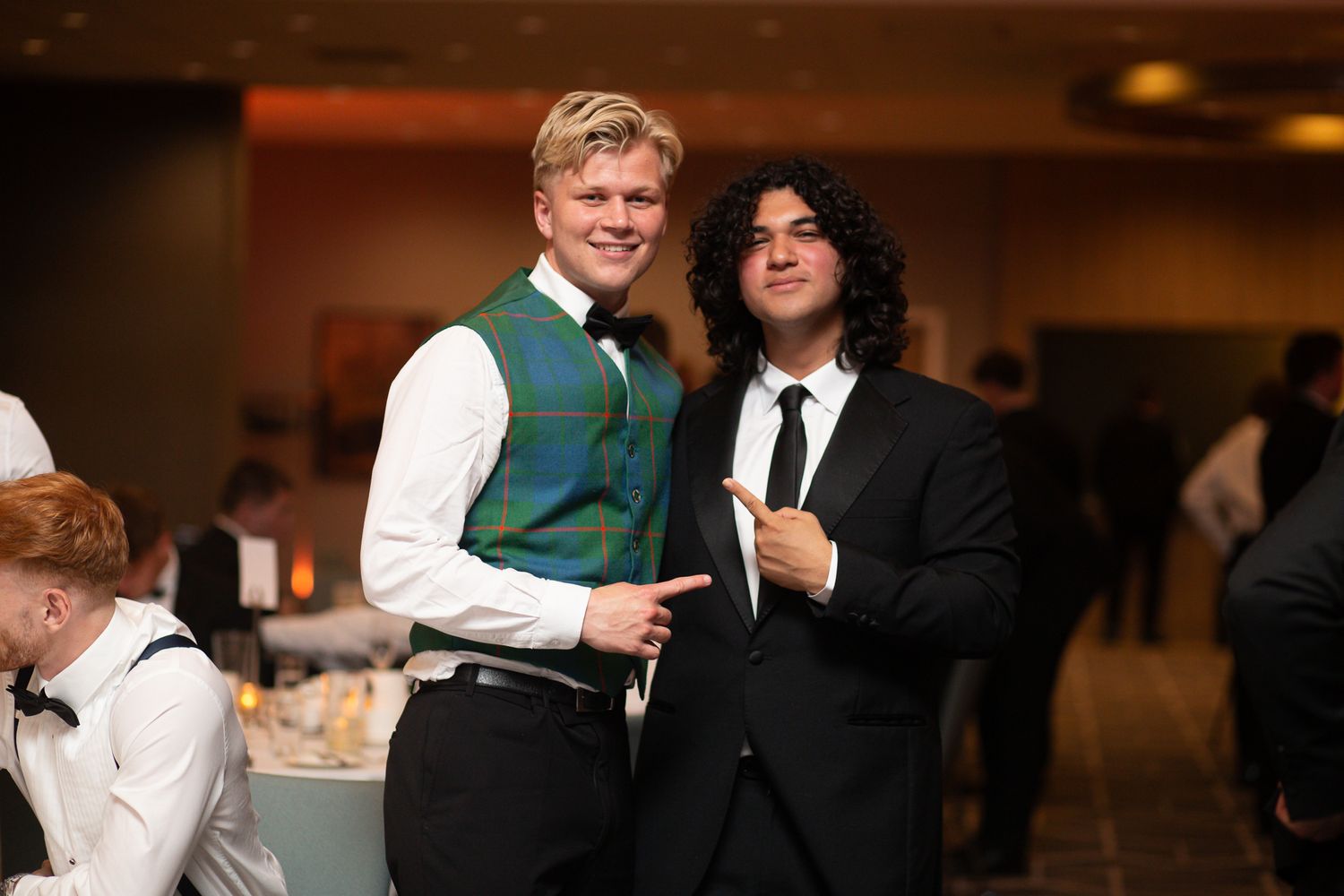 People in formal attire embracing and celebrating at an indoor banquet event.