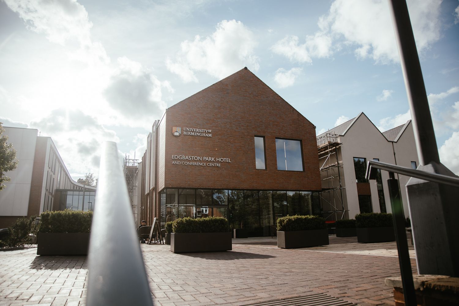 Modern brown brick building with architectural details and landscaping on a sunny day.