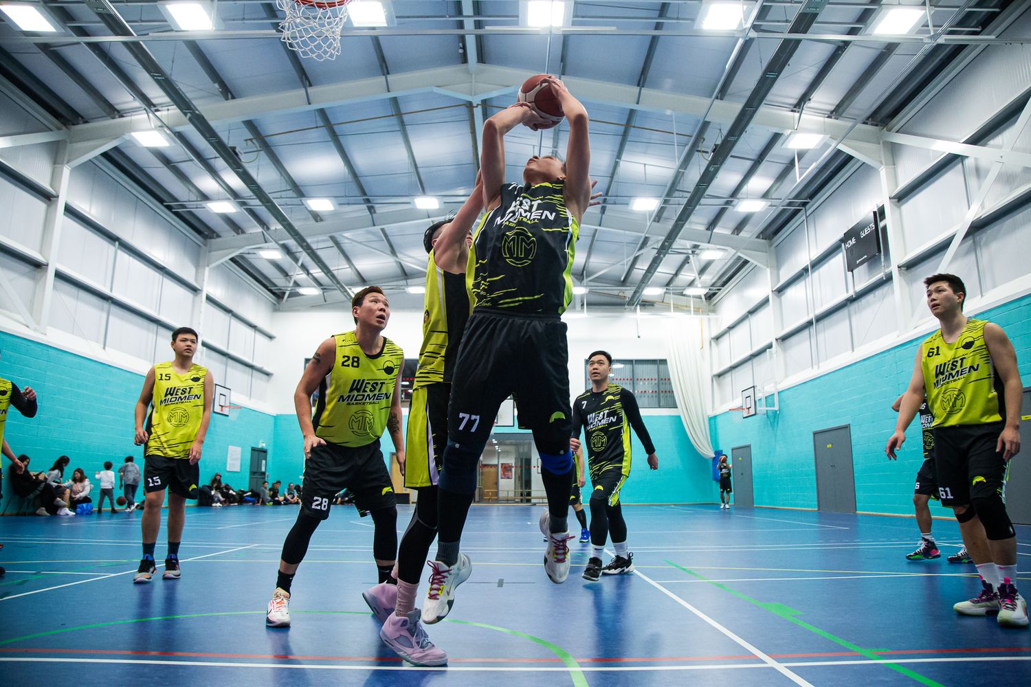 Players competing in an indoor basketball game on a bright blue court.