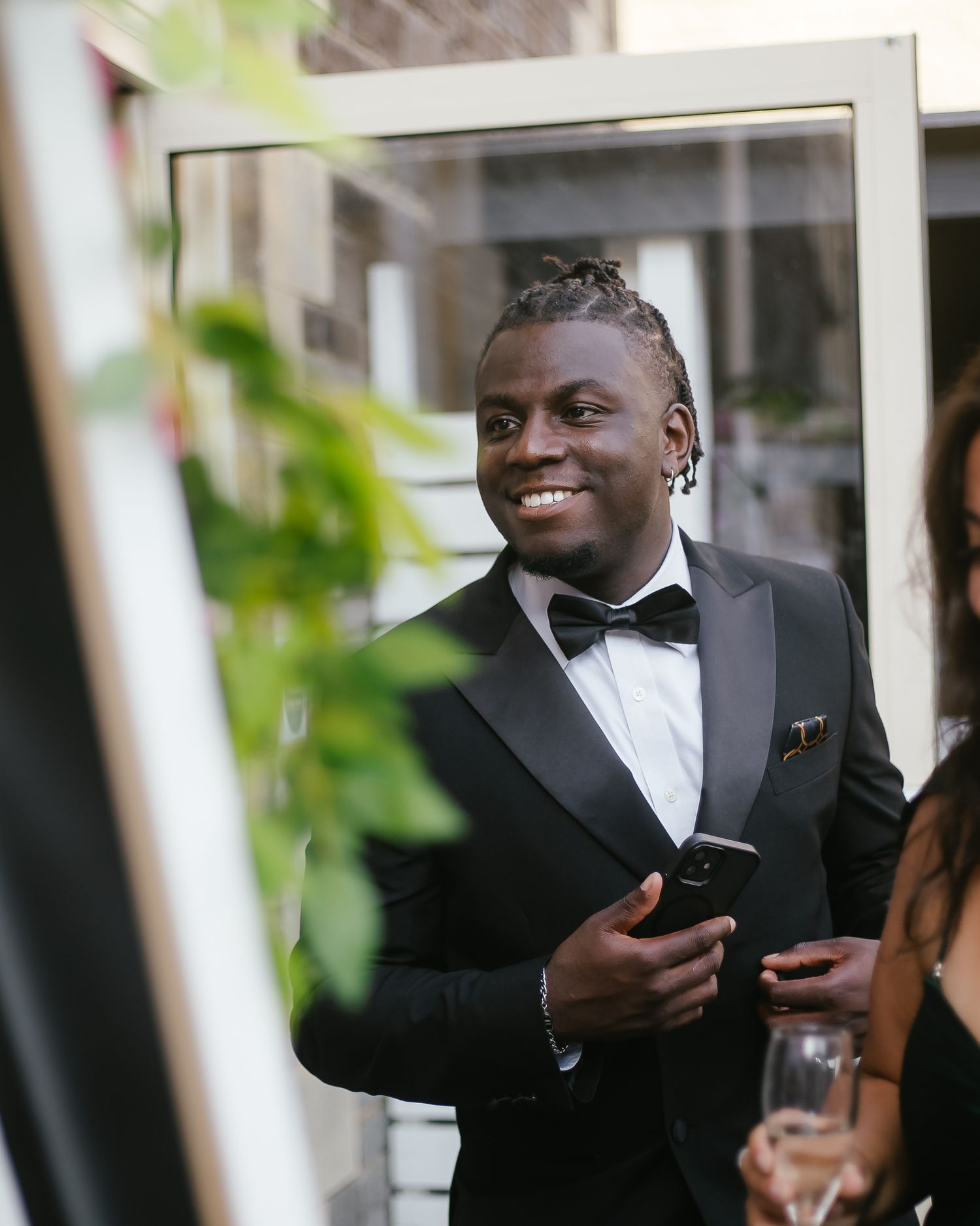 Person in formal attire smiling and reading from a book during a ceremony.
