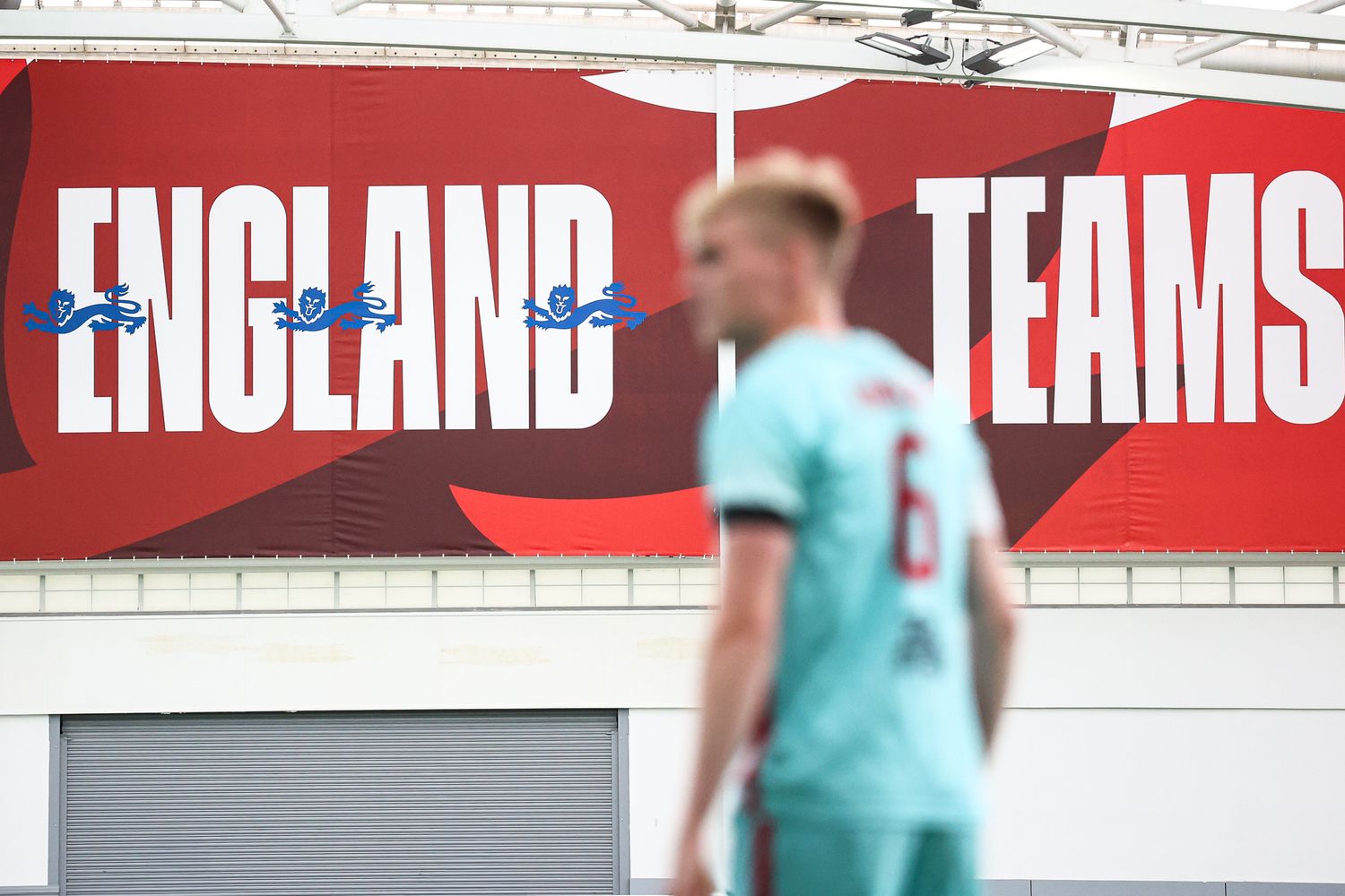 Indoor soccer facility with red England banners displayed on white walls.