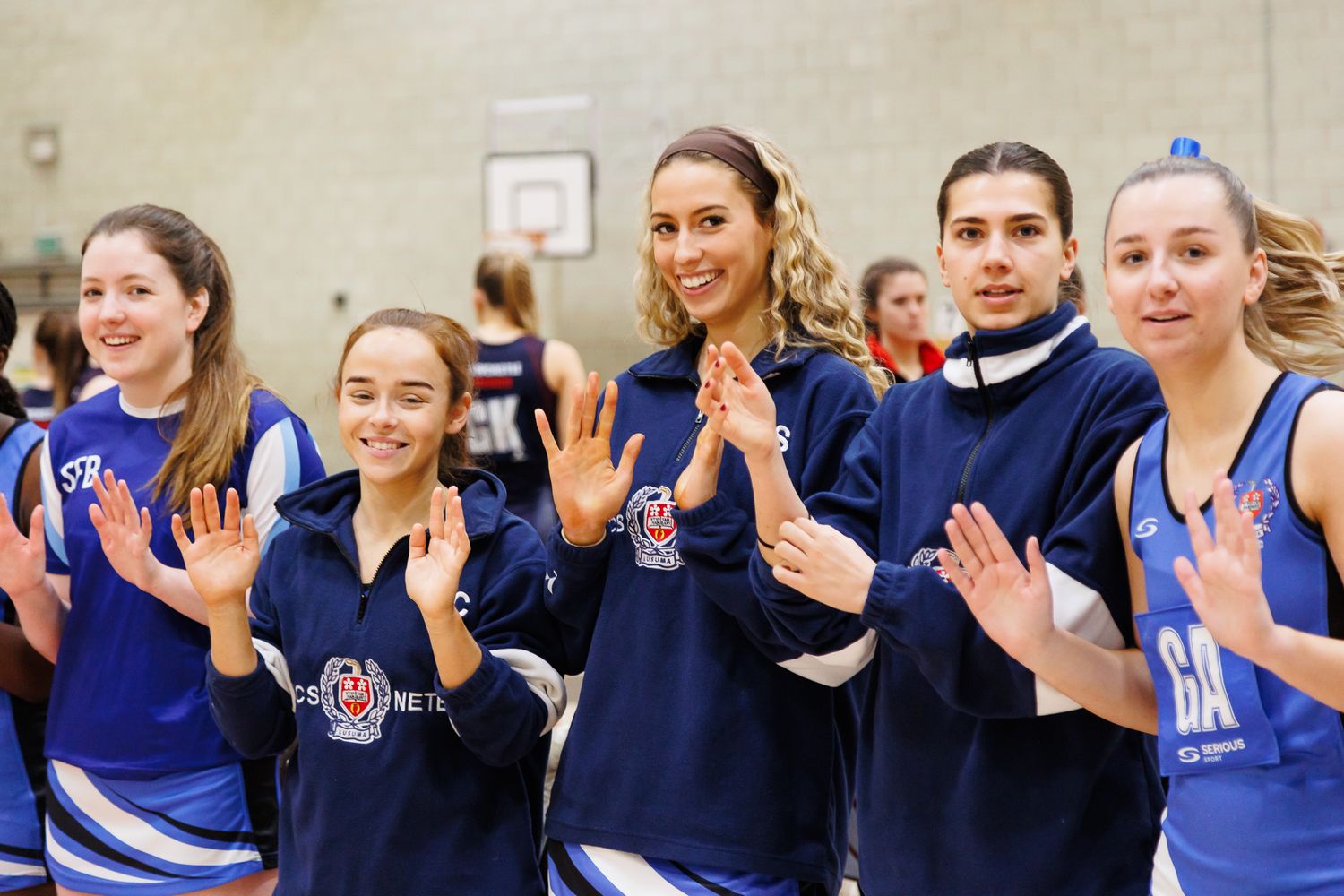 Female athletes in blue jerseys celebrate together as a team.