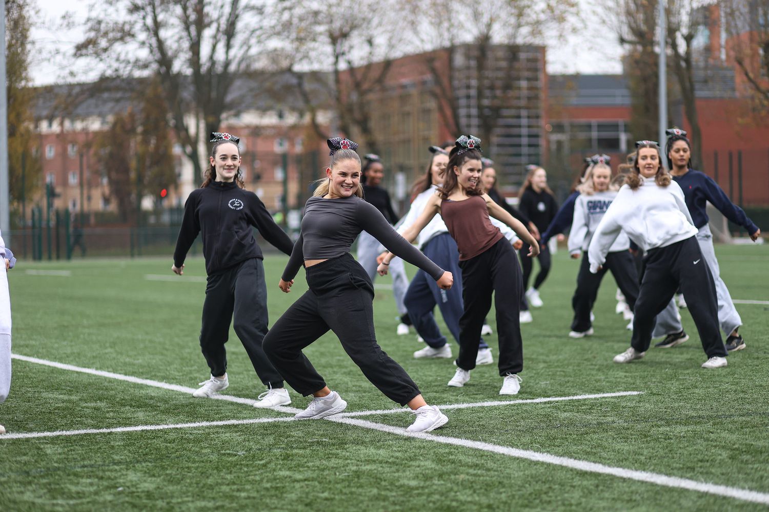 A group of athletes perform synchronized stretching exercises on a sports field during a training session.