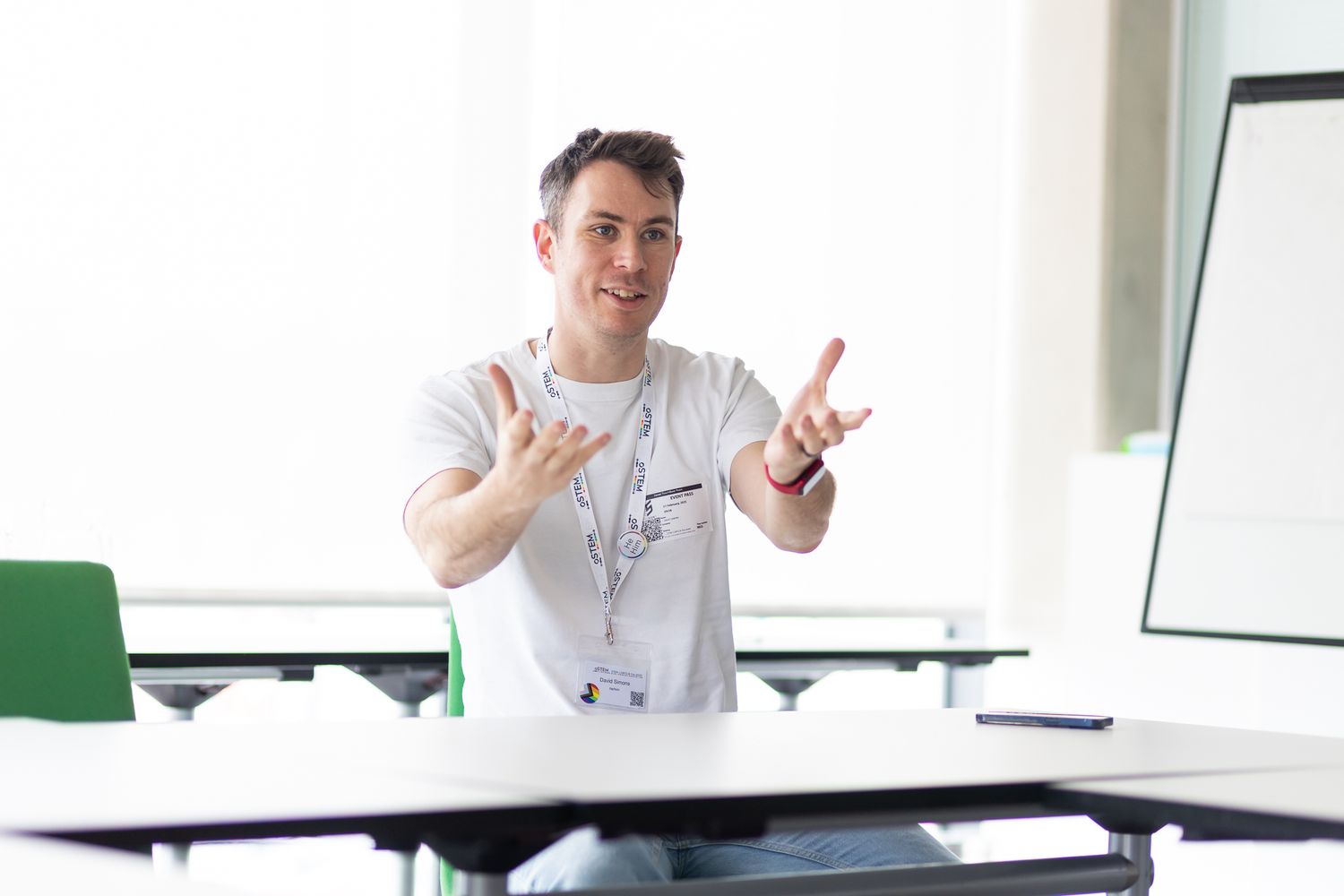 Professional presenter gesturing during a presentation in a bright conference room.