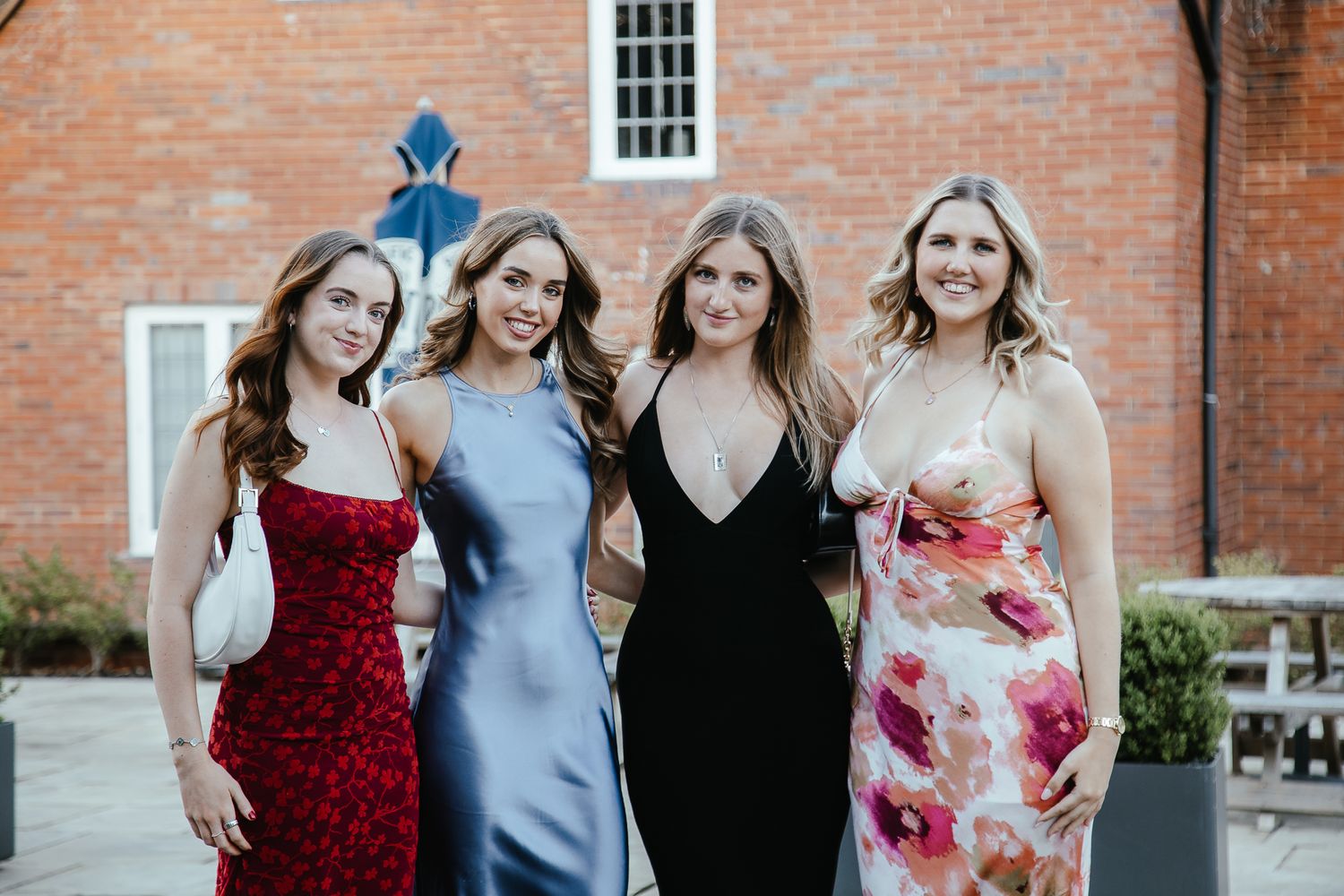 Friends posing together outside a historic brick building during a formal event.