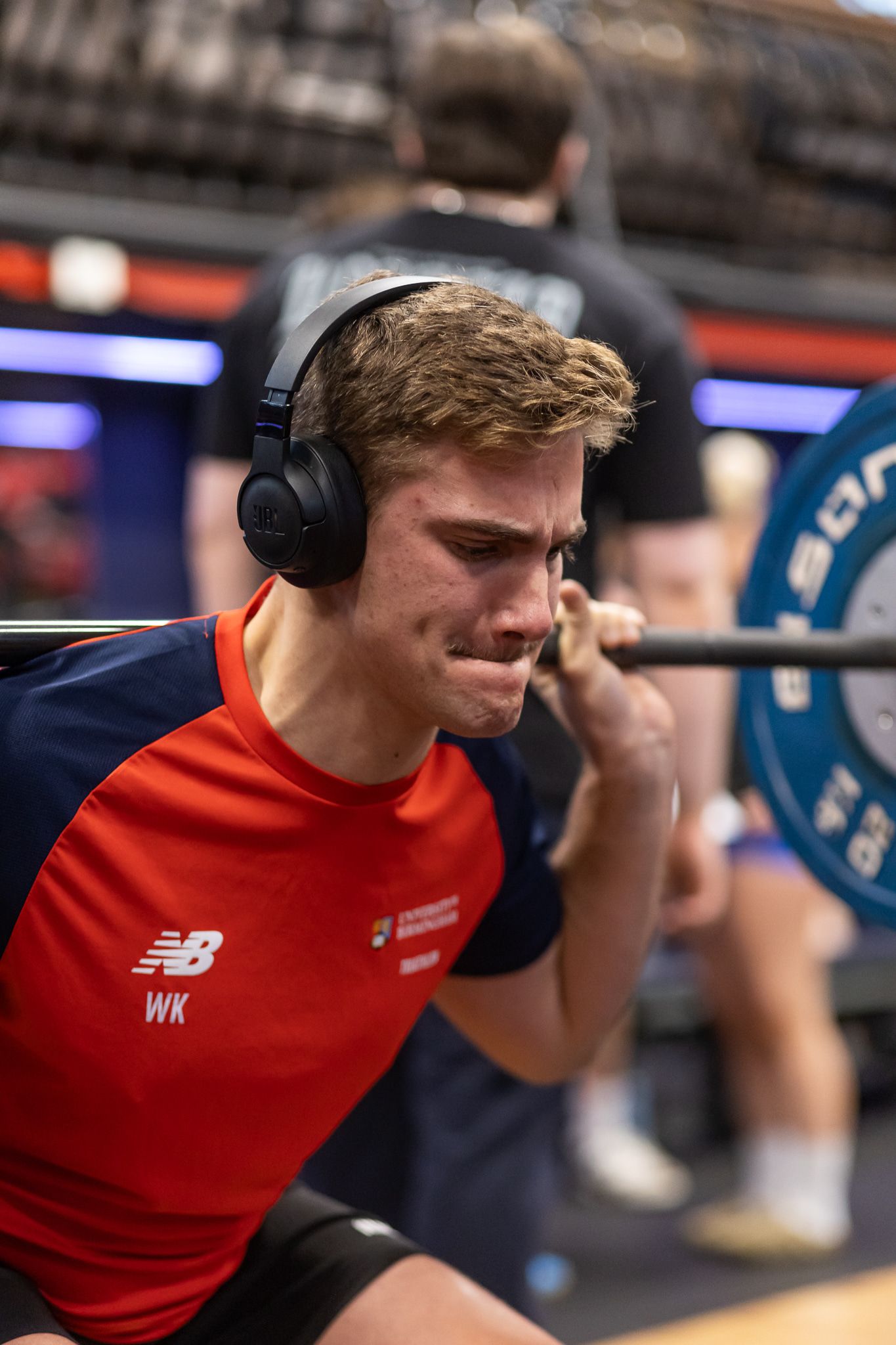Athlete wearing red shirt and headphones during an intense workout session.
