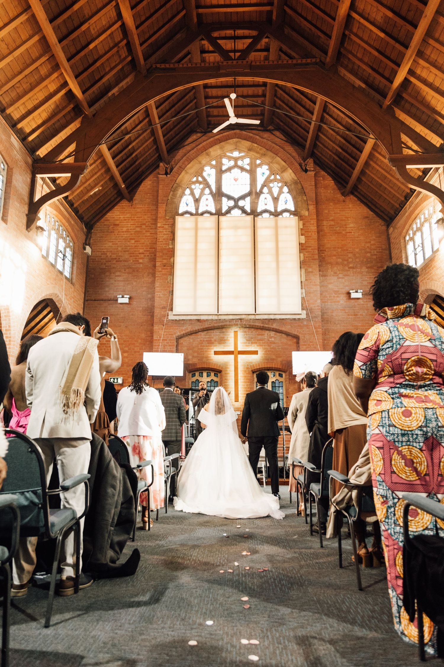 Panoramic view of a church wedding ceremony in a rustic wooden chapel with vaulted ceilings.