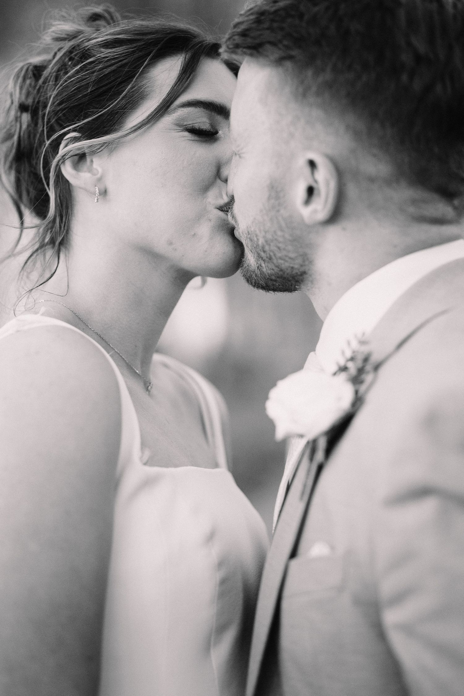 Black and white photo of a bride and groom sharing a tender kiss on their wedding day.