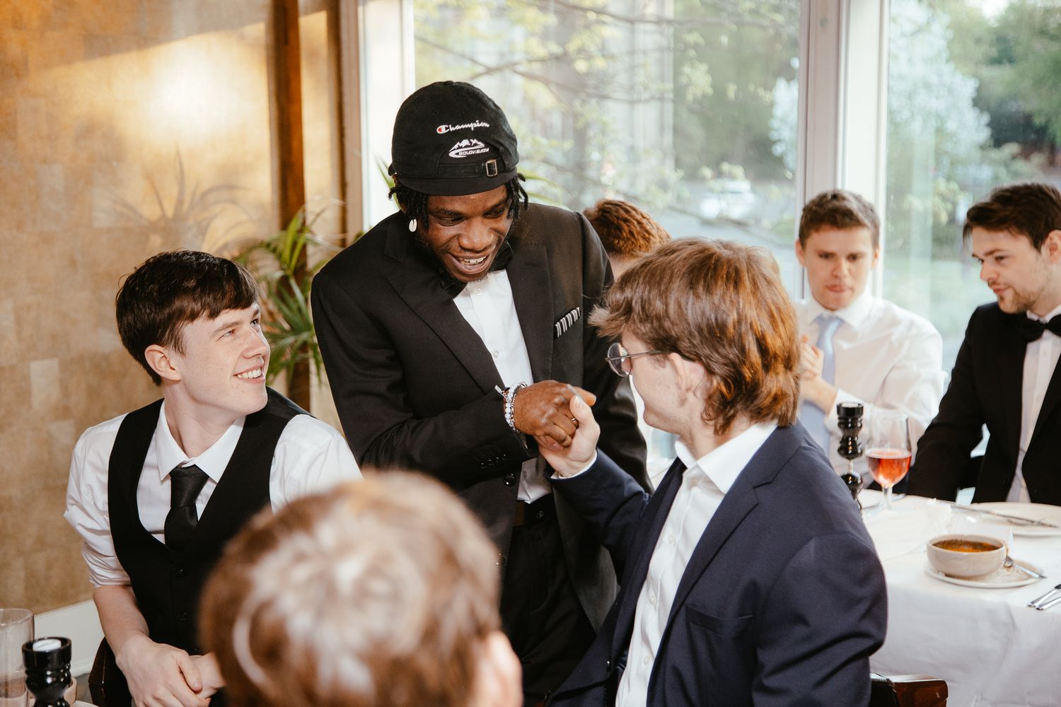 A formal gathering shows people in suits engaged in lively conversation around a dining table.