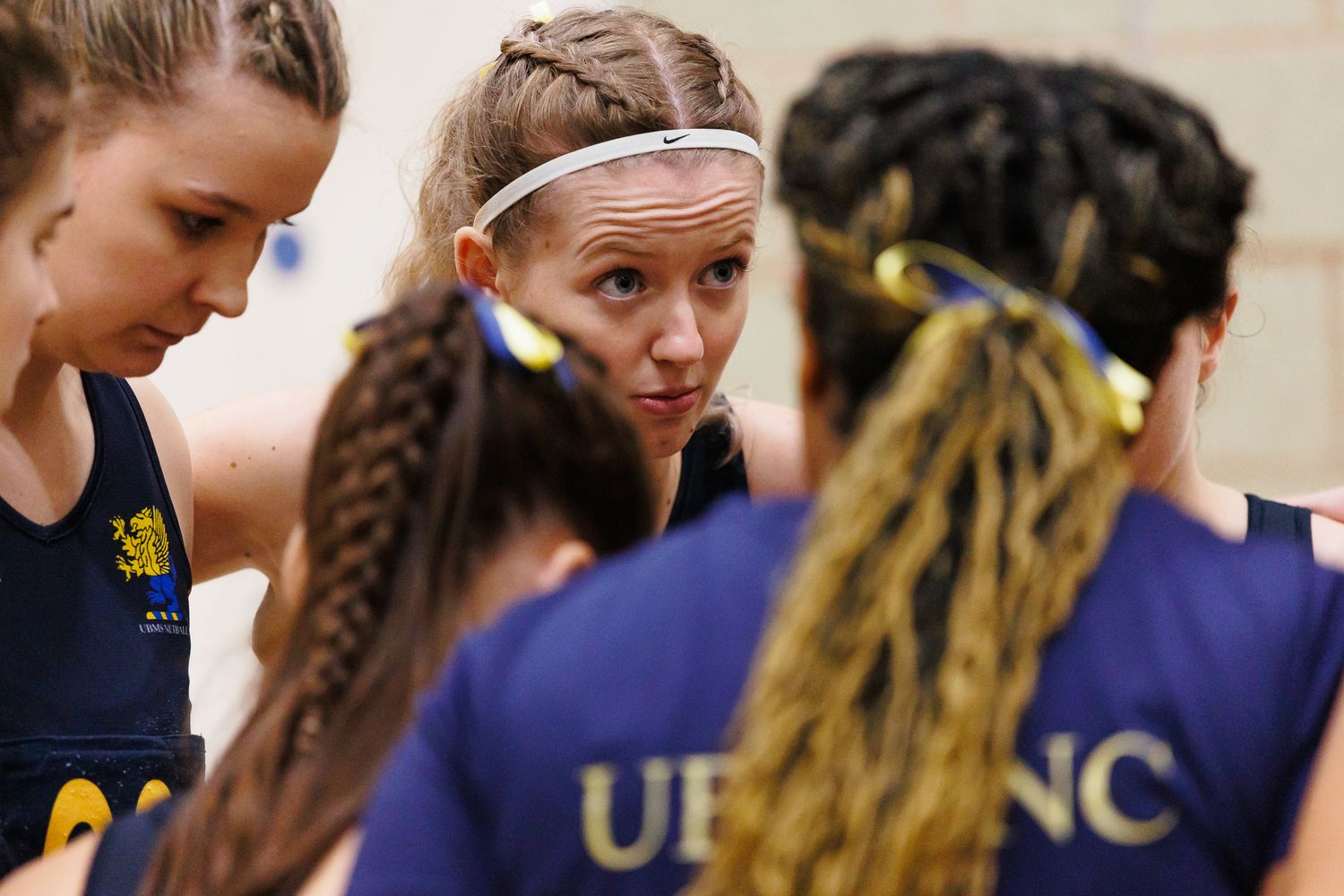 Row of players in navy blue sports uniforms lined up during a netball match.