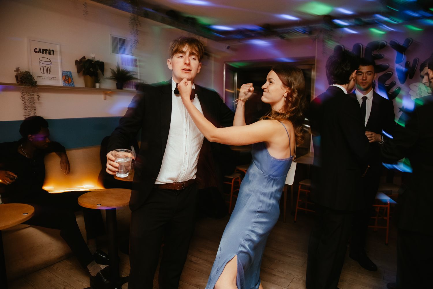 Guests dancing under colorful lights at an indoor celebration.