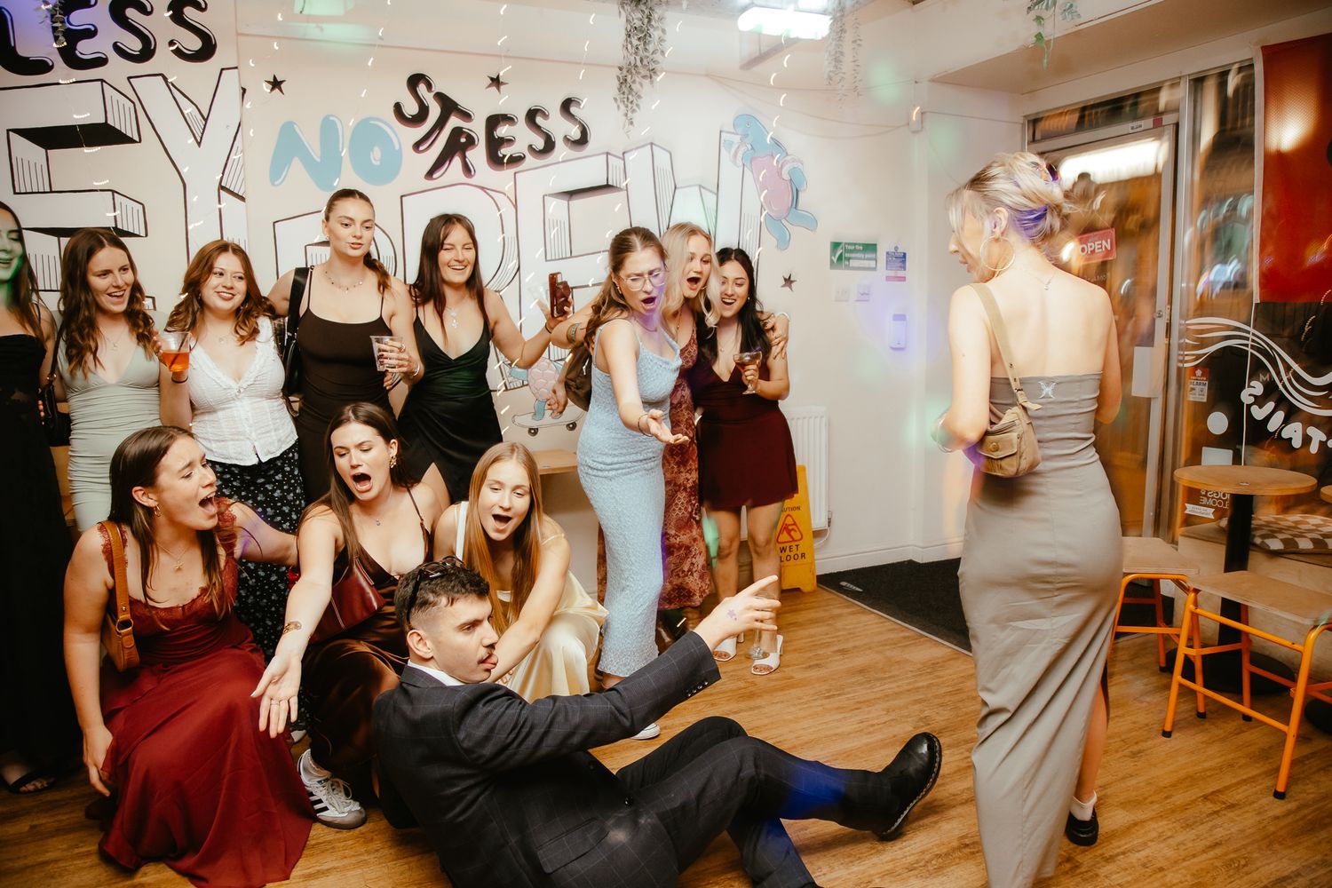 Party attendees in formal wear gathered in a room with graffiti-style wall art.
