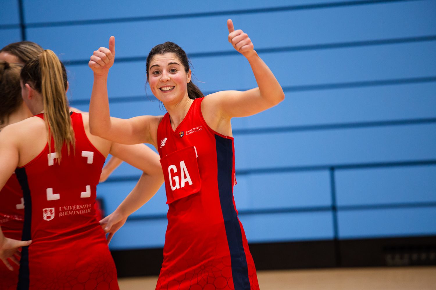 Athletes in red uniforms celebrating during an indoor sports match.