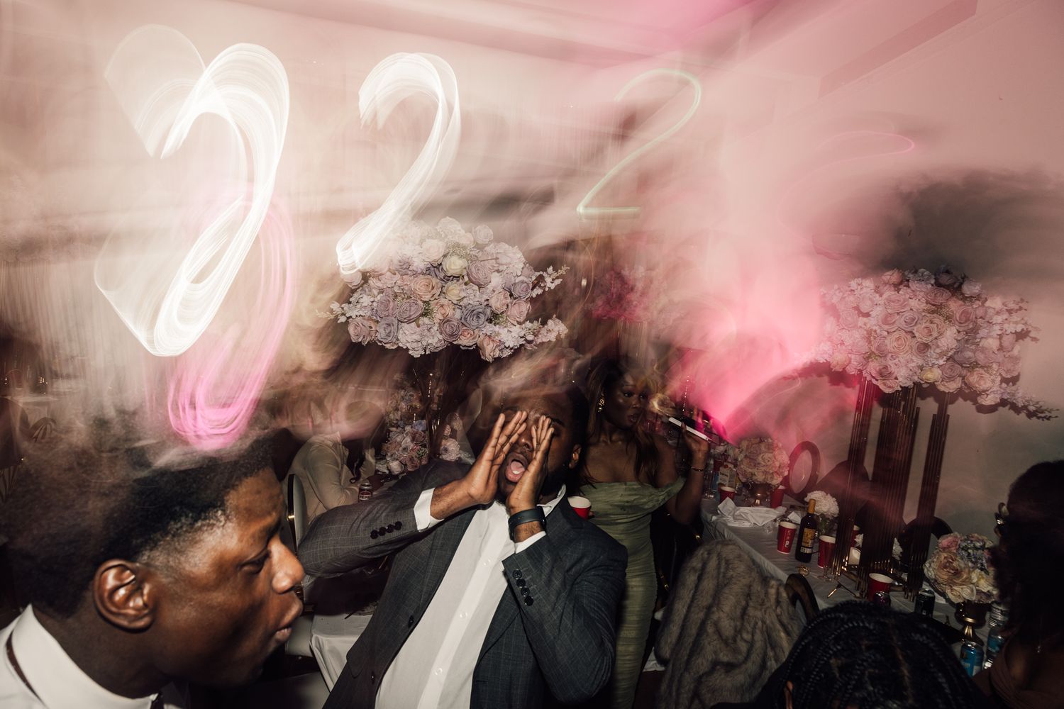 Pink ambient lighting fills a crowded room with dancing and celebration.