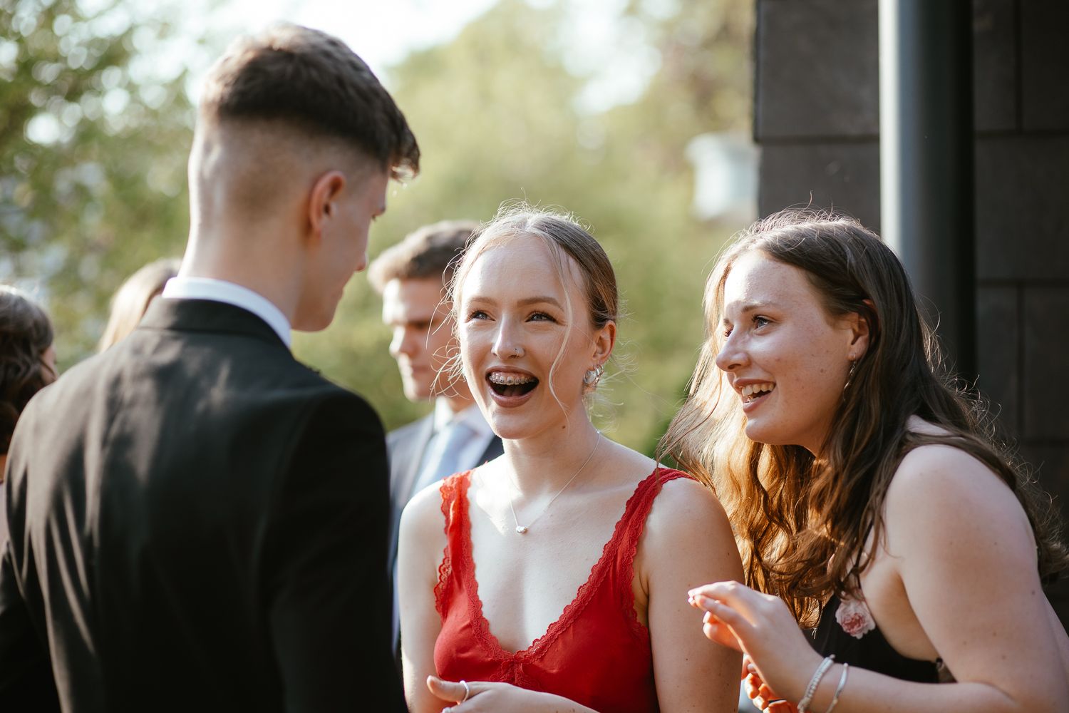 A group of formally dressed guests share joyful moments at an outdoor event.