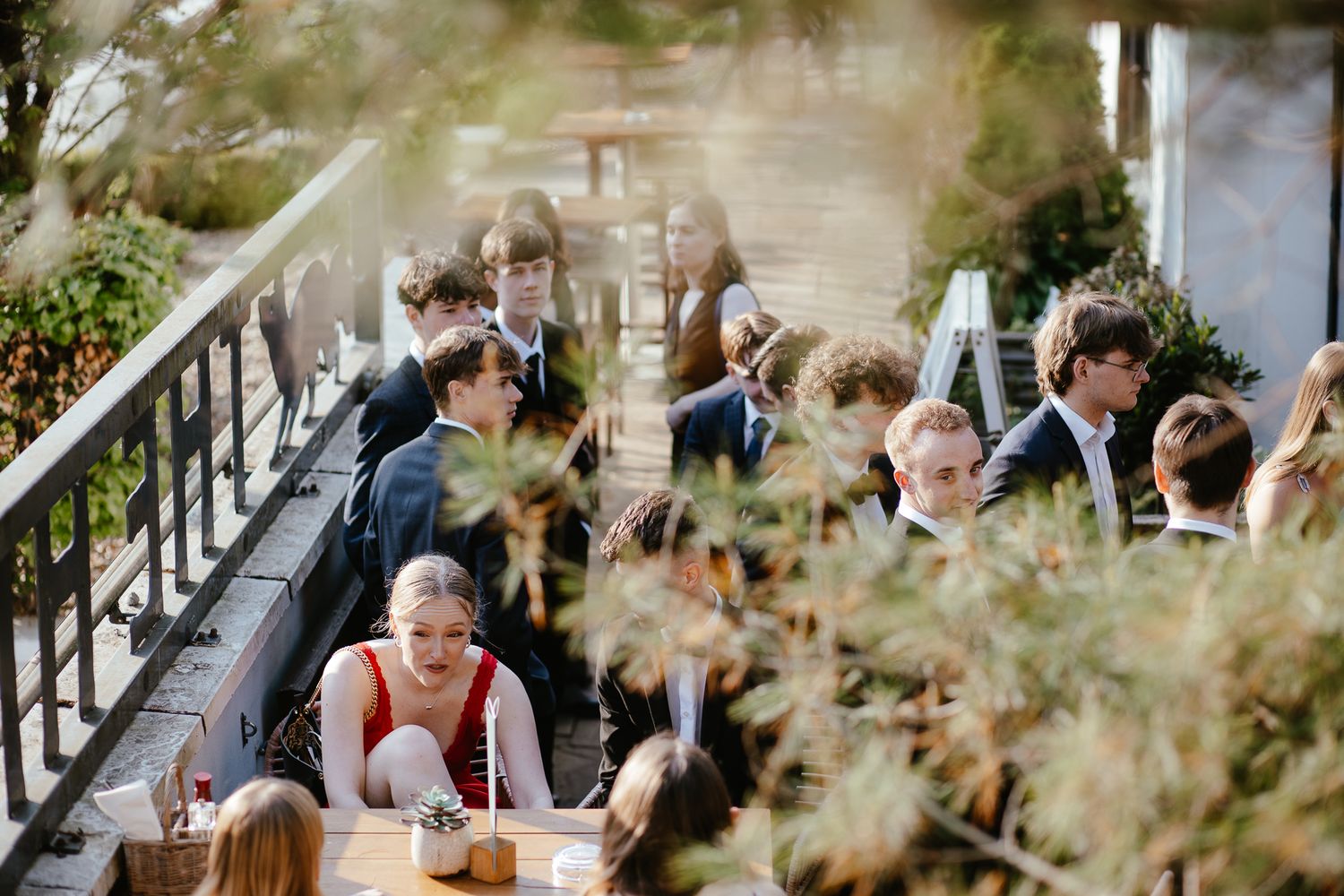 Guests enjoying a wedding celebration on an outdoor patio with decorative railings.