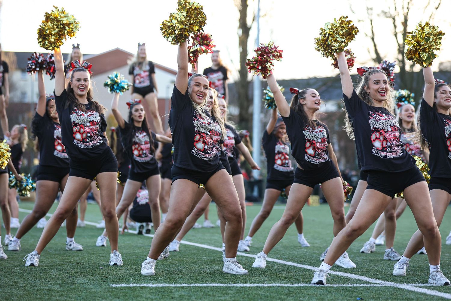 Dance team members execute precise formations during an outdoor performance in matching attire.