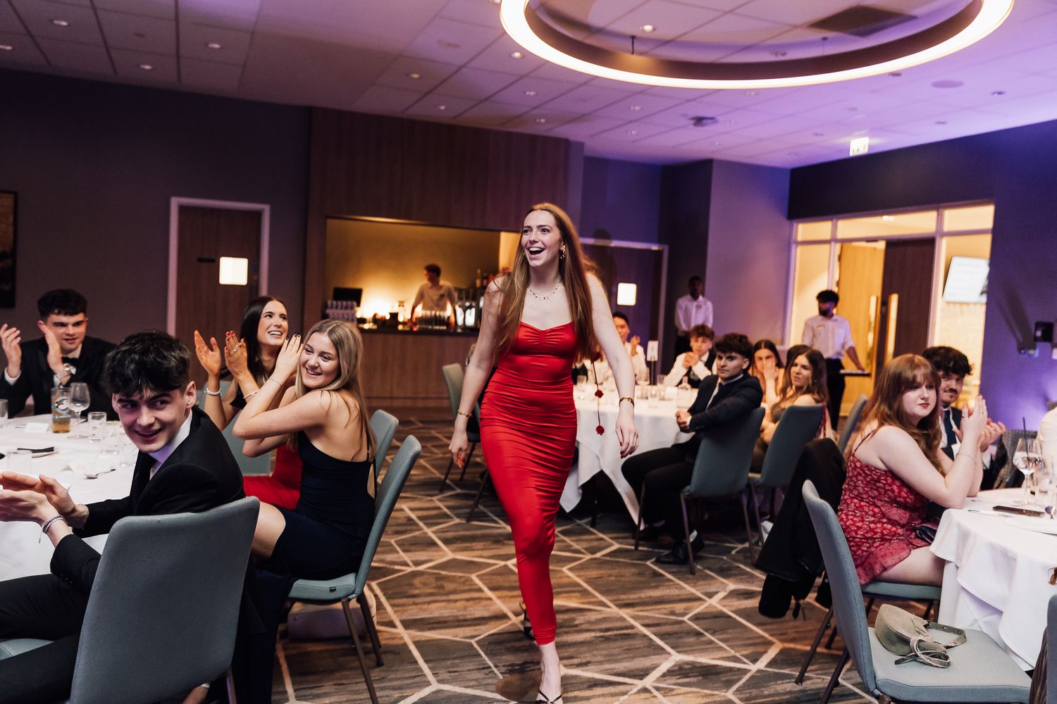Event space with modern lighting and people mingling at round tables.