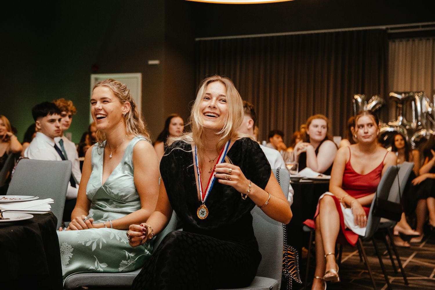 Wedding reception guests laughing and enjoying entertainment in a banquet hall.