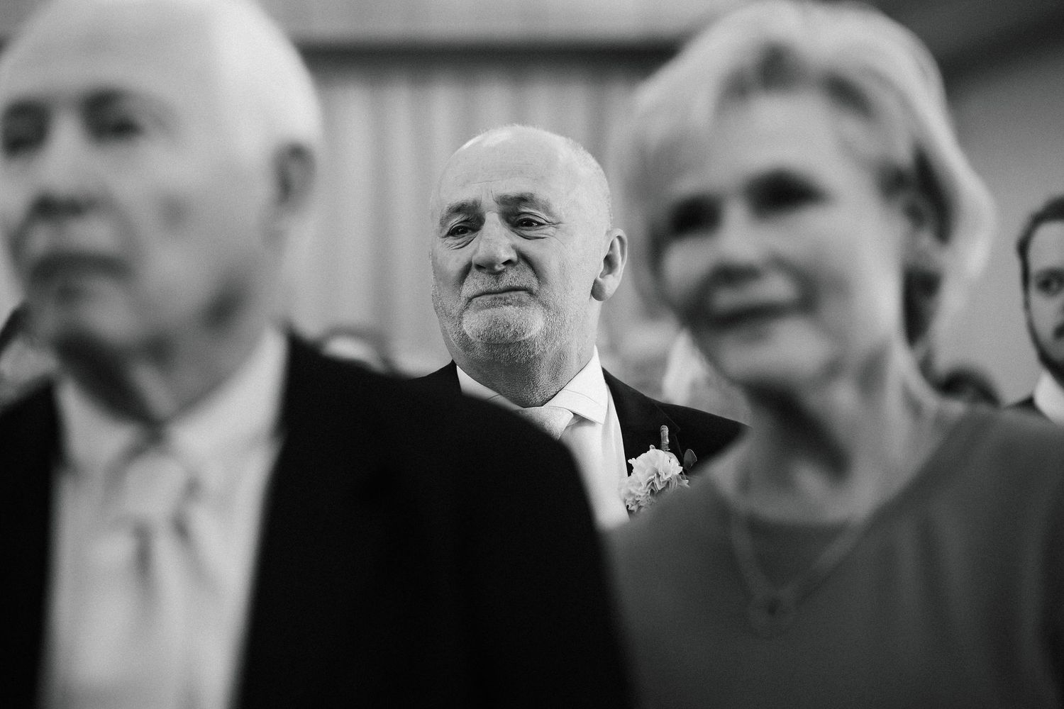 Emotional wedding guests watching the ceremony in a black and white candid photo.