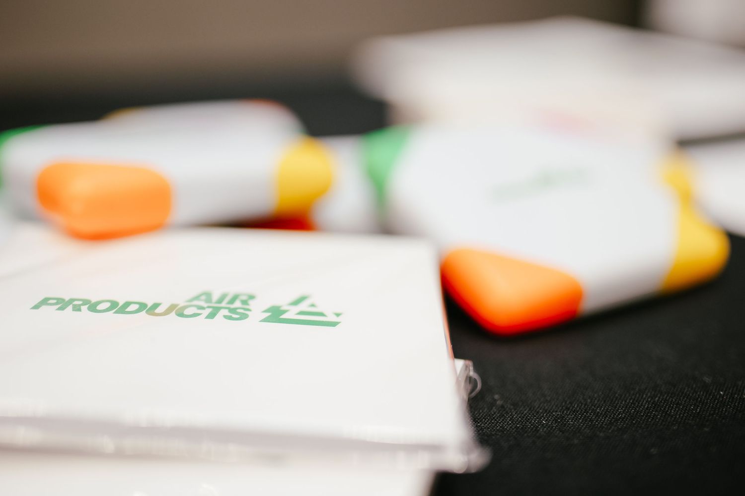 Office supplies and branded materials arranged on a dark surface in a professional setting.