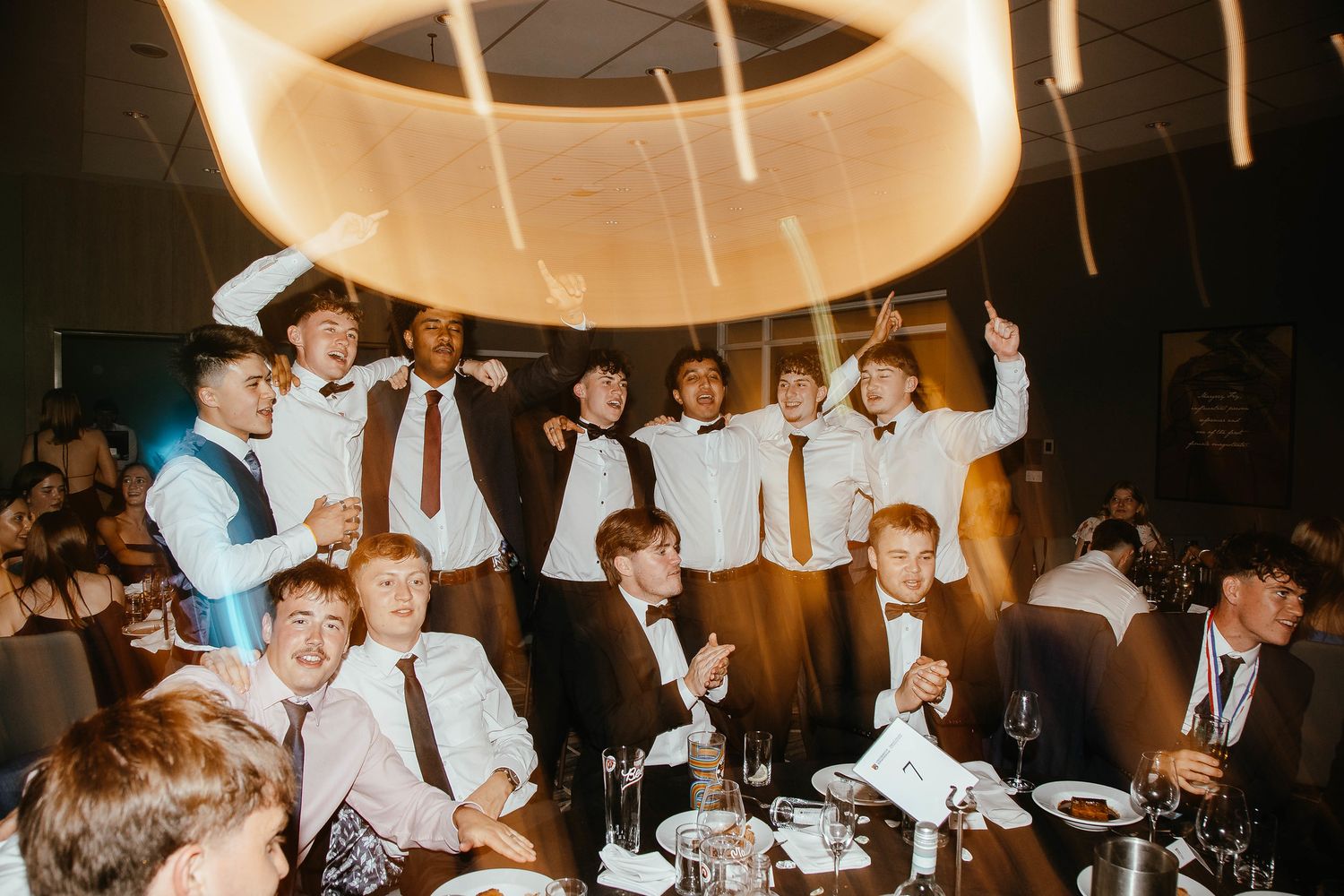 Party scene in warm lighting showing people dancing and celebrating.
