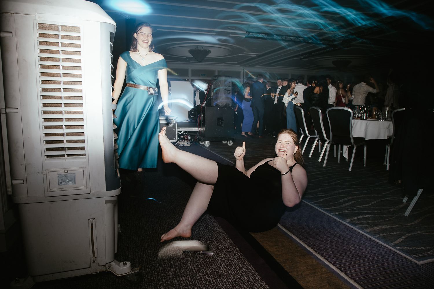 Dark venue illuminated by blue lights with people dancing and having fun.